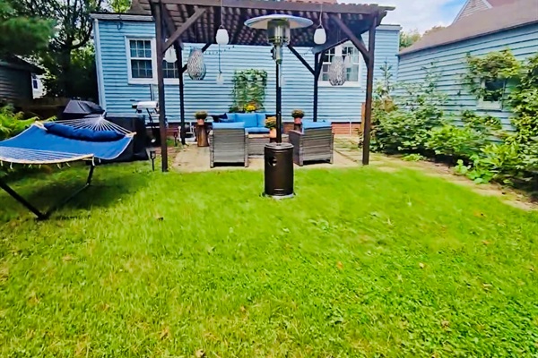 Backyard comfort at its finest—stretch out in the hammock, warm up by the patio heater, and gather under the pergola with the patio set nearby. Solar lanterns add a soft glow as the evening unfolds.