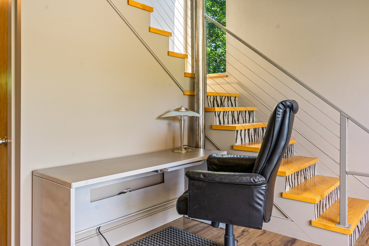 Work remotely with ease at "The Crag." This dedicated office nook under the architectural staircase features a long work desk, executive leather swivel chair, desk lamp, and power outlets—ideal for staying connected during your stay.