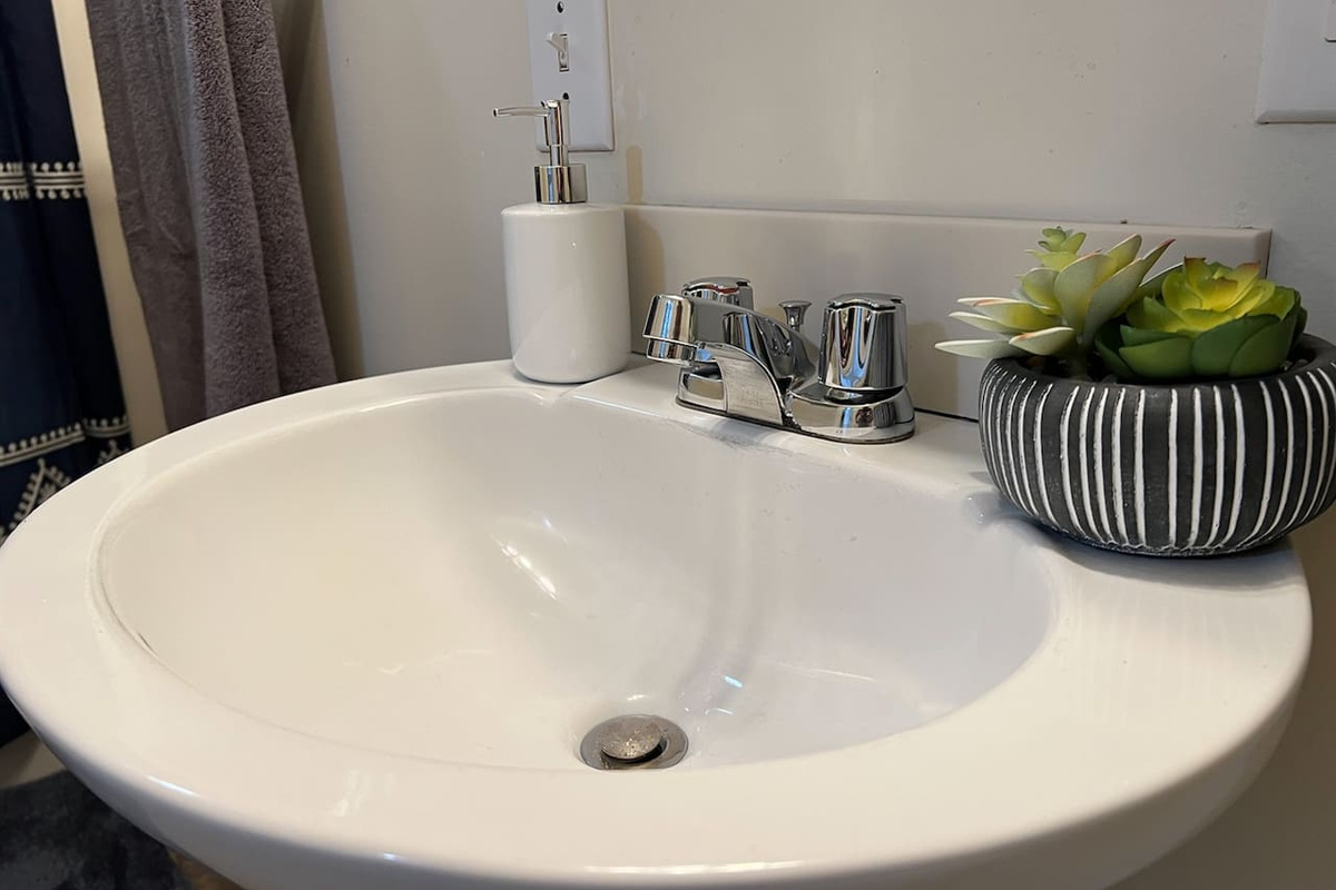Modern full bathroom featuring a sleek sink with a stylish faucet and tasteful decorations—designed to offer a clean, functional space with a touch of elegance and contemporary charm