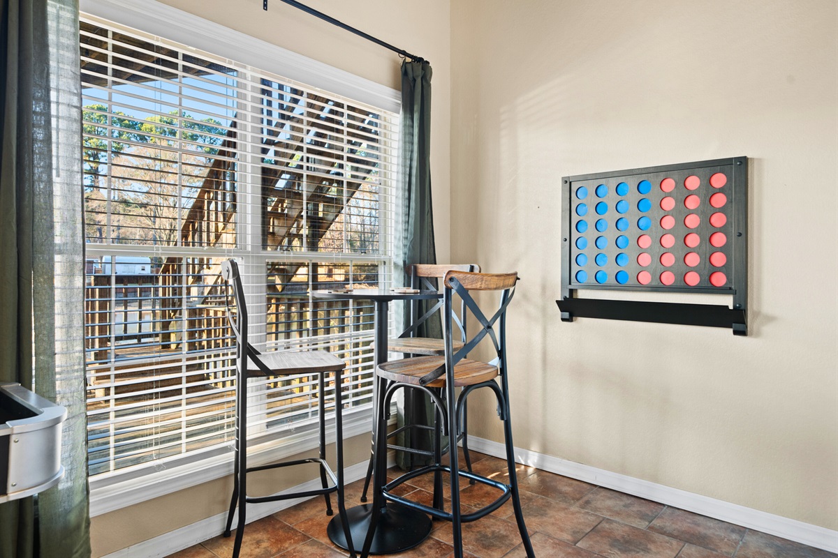 A wall-mounted Connect Four game adds a nostalgic touch, offering guests of all ages a simple and joyful way to unwind while enjoying the natural light from the nearby windows.
