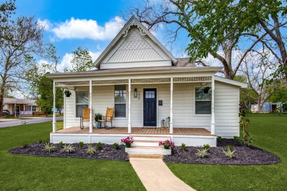 Charming single-story modern farmhouse. White board-and-batten siding, covered front porch, flower-lined walkway, and manicured landscaping. Walkable to downtown Aubrey dining and coffee in Denton County.