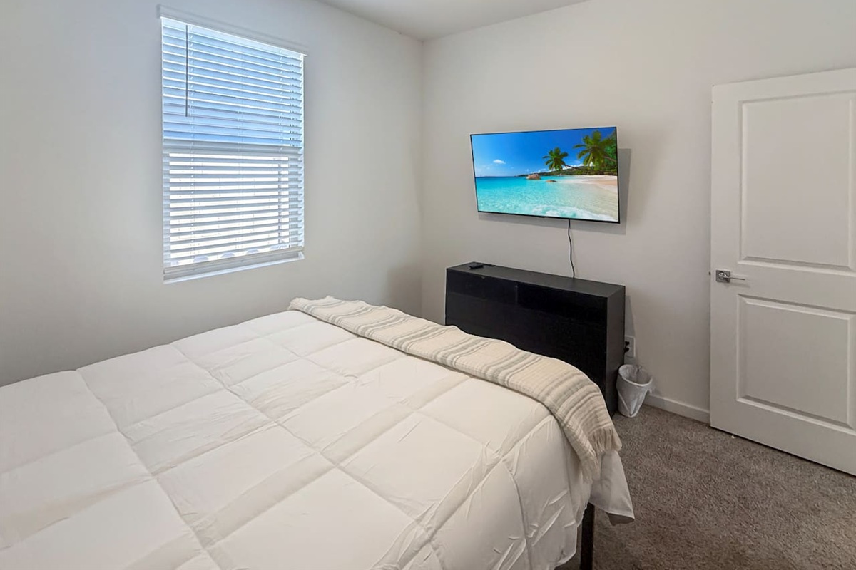 Bedroom with bed, TV on dresser, window, and closet door