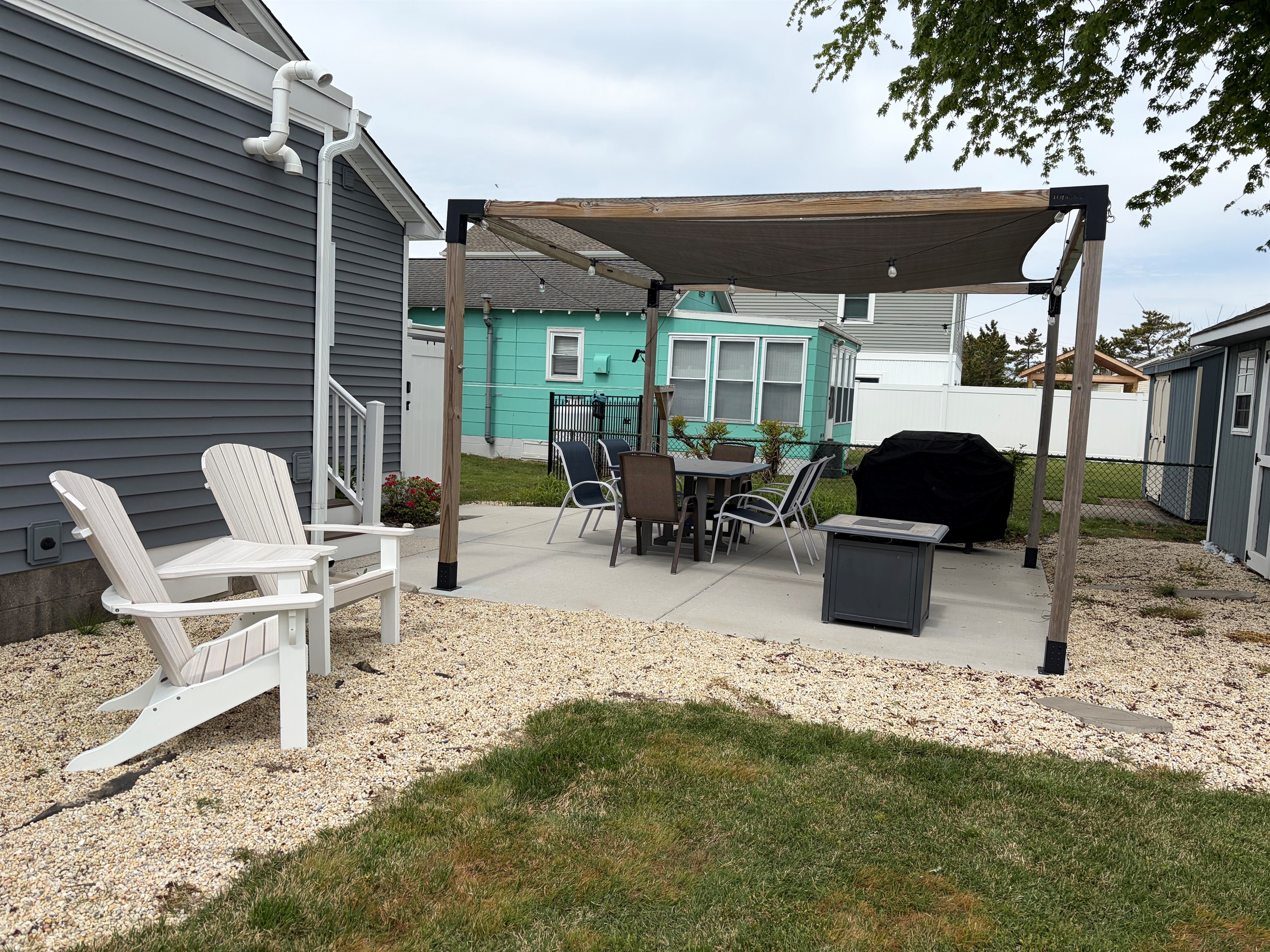 Backyard seating area, table, chairs, fire pit, and grill.