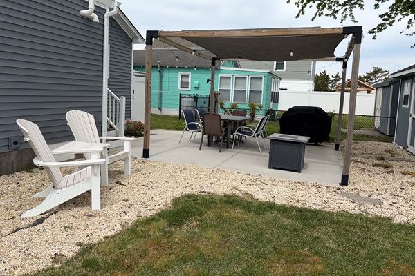 Backyard seating area, table, chairs, fire pit, and grill.