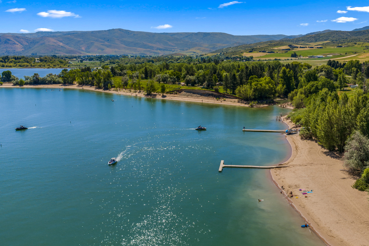 Aerial view of Pineview Reservoir showcasing sandy beaches, boat docks, crystal-clear water, and the breathtaking beauty of Ogden Valley.