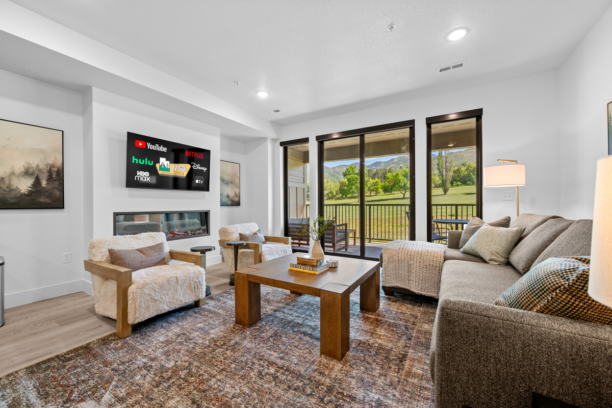Spacious open-concept living area with fireplace, Smart TV, and golf course views.