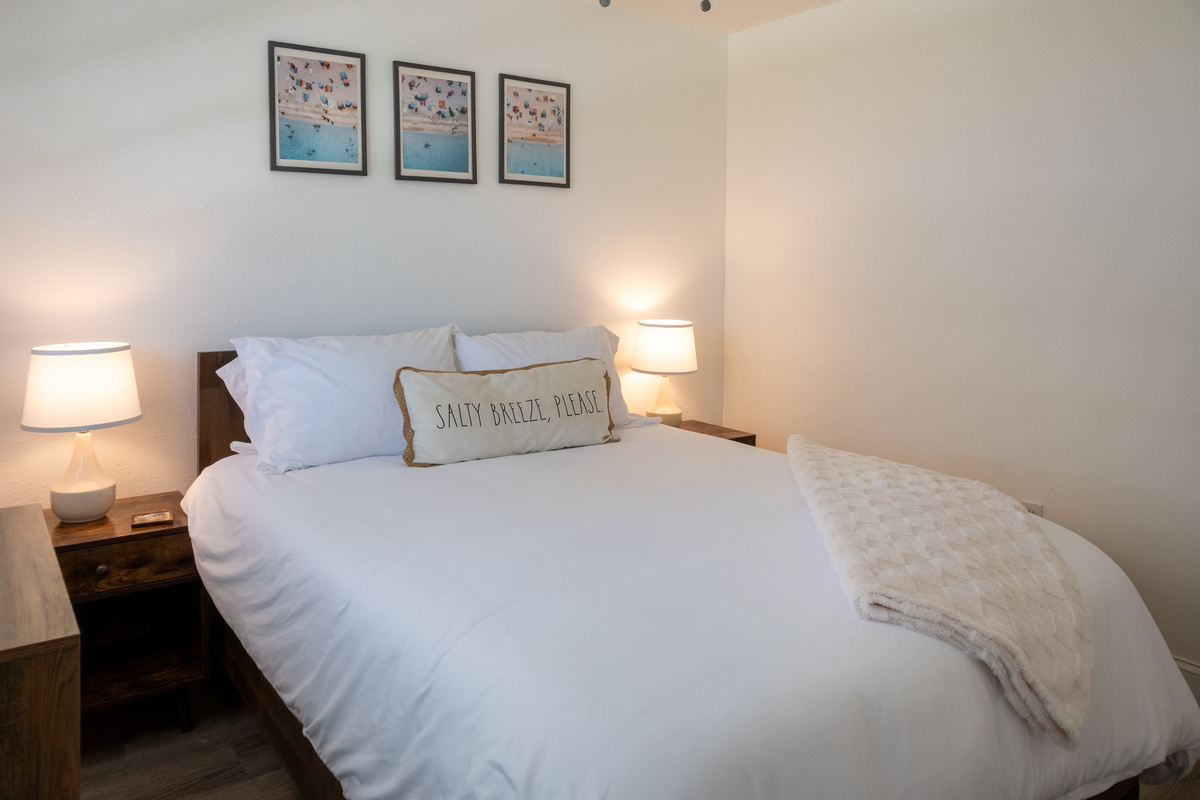 Bedroom 1: plush queen bed with crisp hotel-quality linens – salty breeze, please