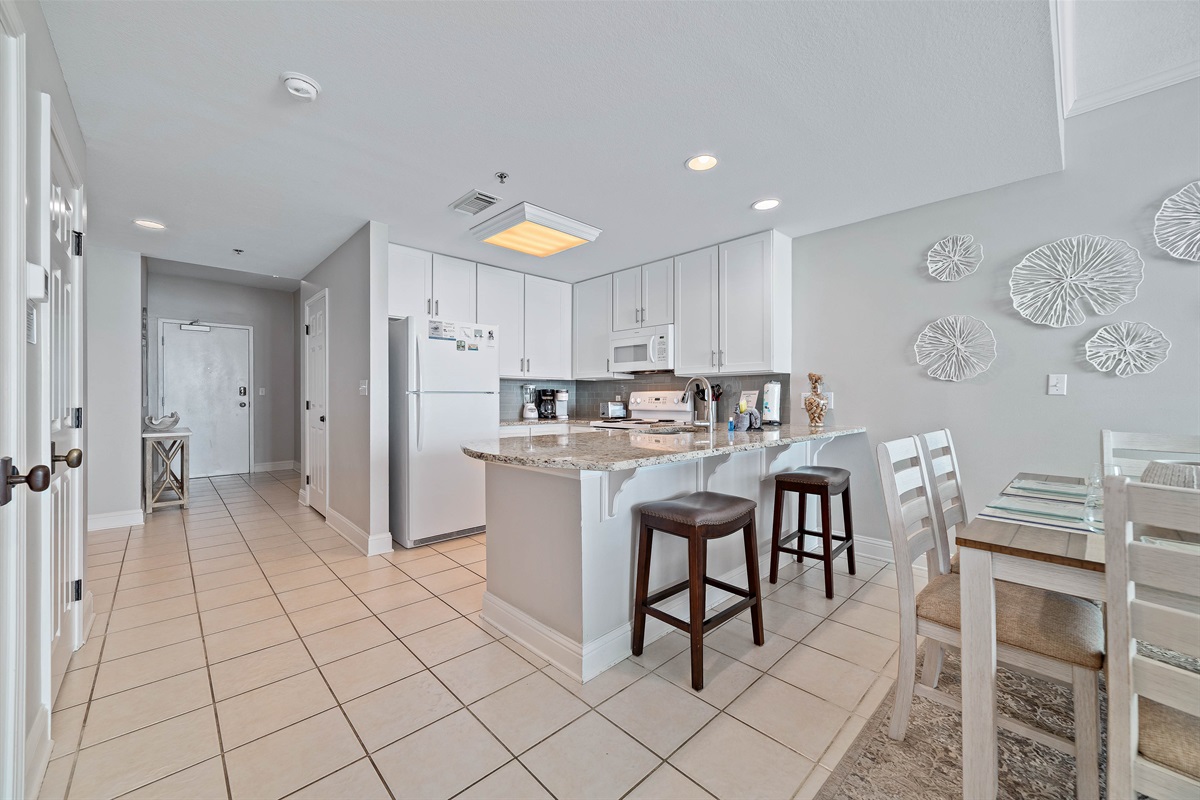 The large island with a breakfast bar provides a central hub for conversation and dining. Whether you're enjoying a quick bite or mingling during a get-together, this area combines comfort and function with style.