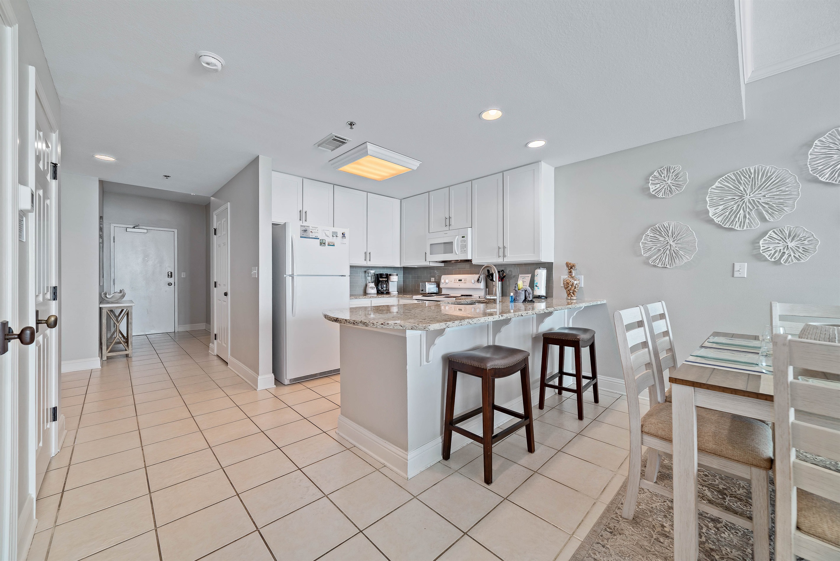 The large island with a breakfast bar provides a central hub for conversation and dining. Whether you're enjoying a quick bite or mingling during a get-together, this area combines comfort and function with style.