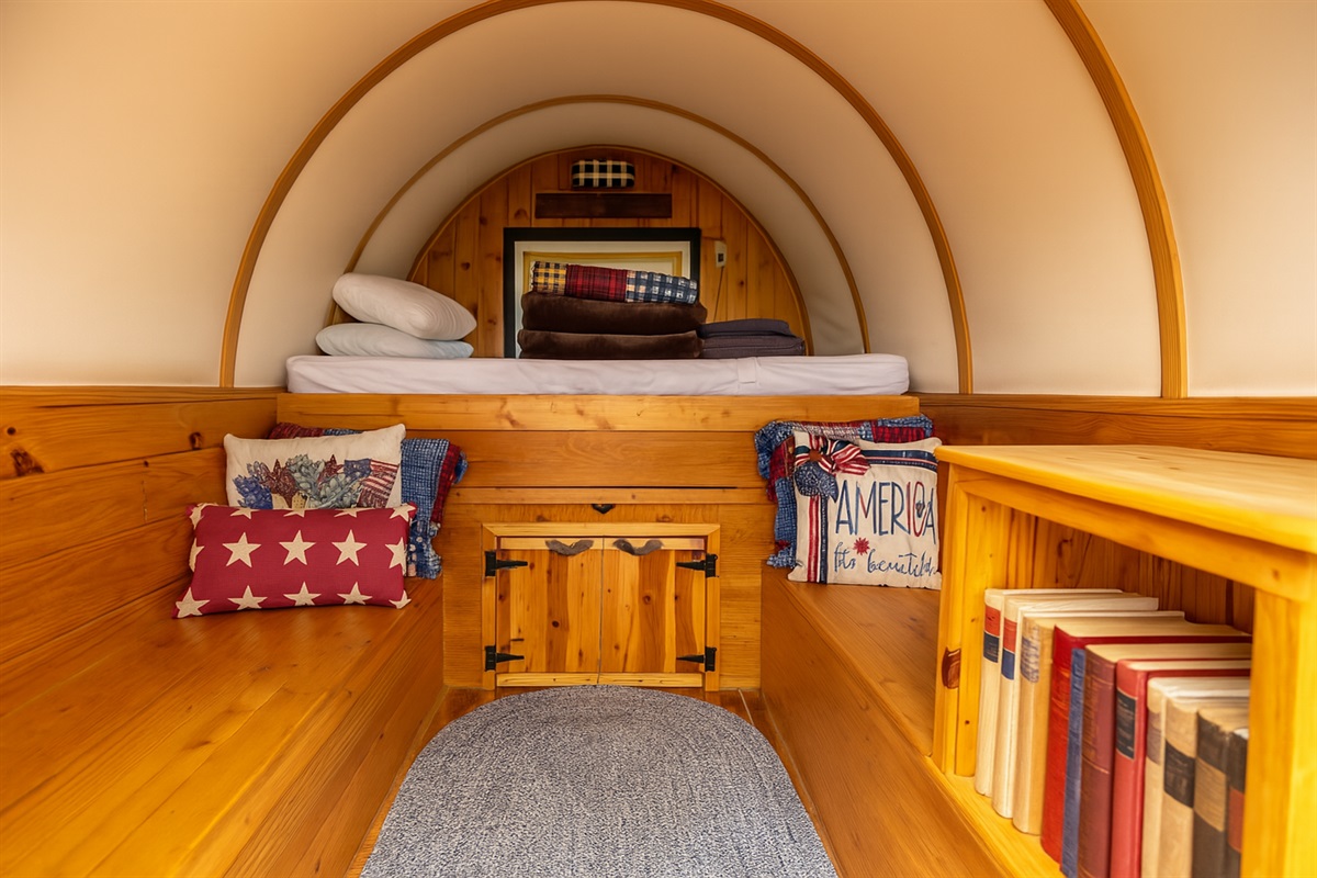Raised full-size bed with layered linens and dual pillows.