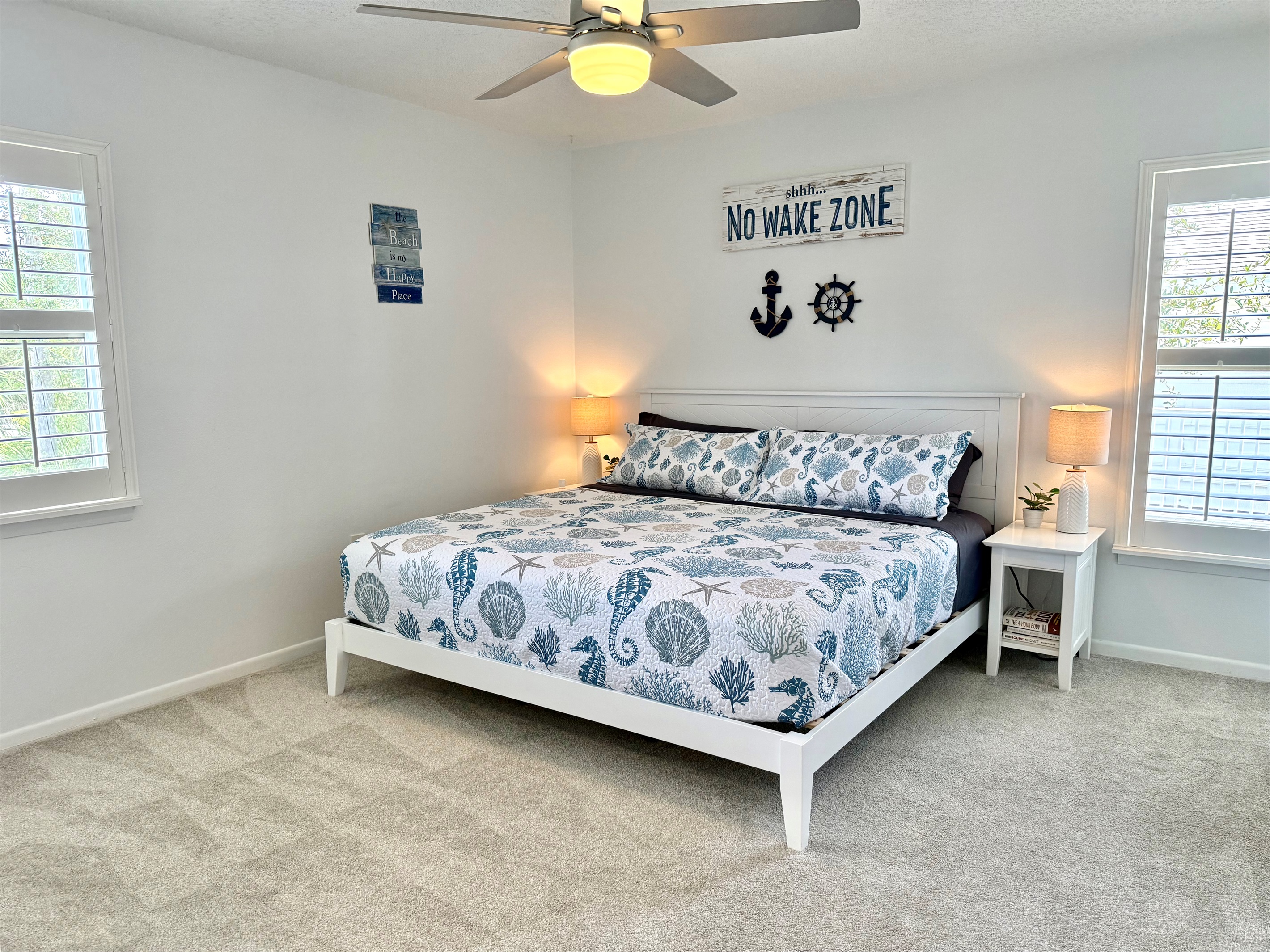 Spacious king suite with soft carpet, coastal décor, and plenty of natural light — your private retreat.