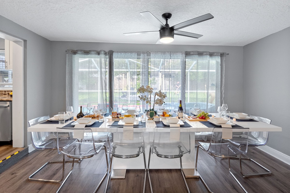 Surrounded by floor-to-ceiling windows with sheer curtains, this dining space is filled with natural light and peaceful views of the backyard.