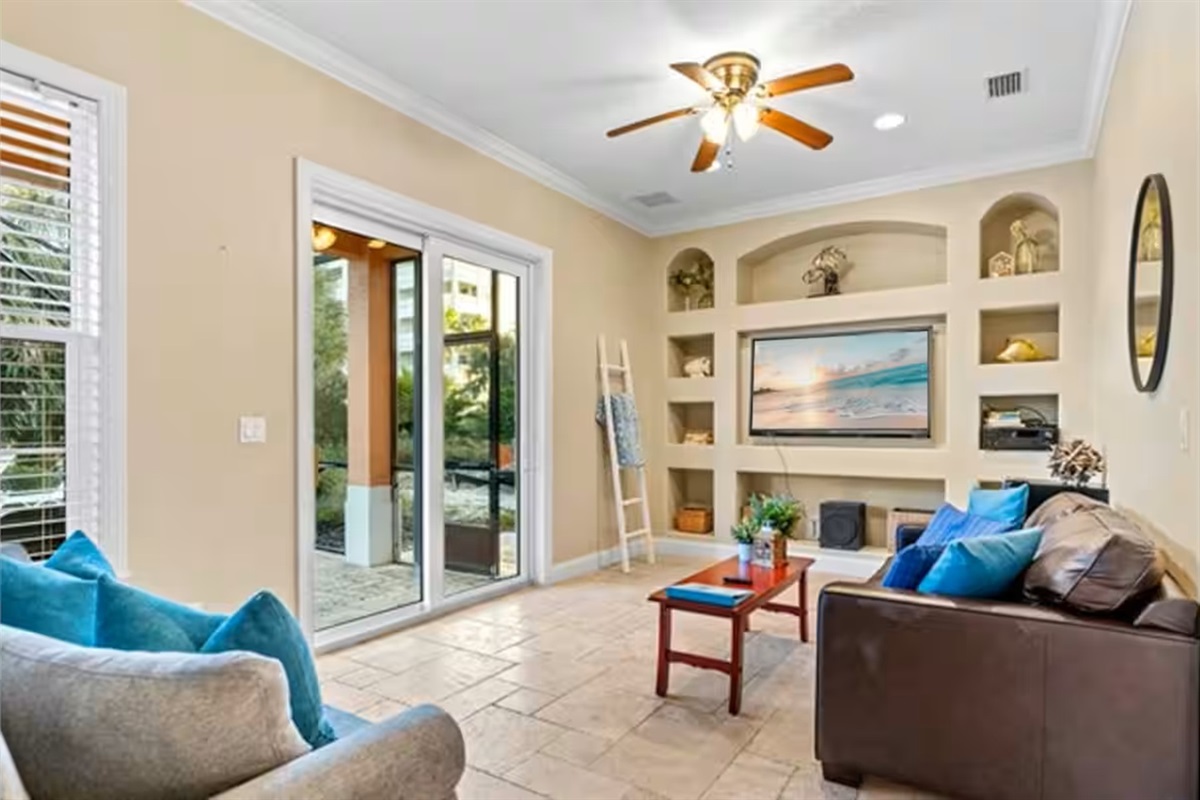 Spacious, sunlit living room made for relaxing 🛋️
Built-in shelving, comfy seating, and direct pool access create the perfect spot to unwind, stream a movie, or gather after the beach.
