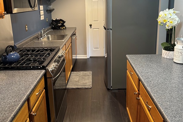 Inside view of the kitchen area with stove, microwave, refrigerator and more.