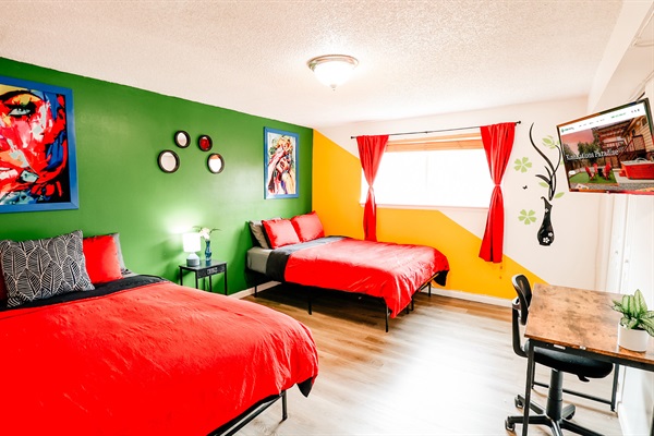 A room where a lively green wall meets a cheerful yellow counterpart, framed by rich red curtains and complemented by cozy red bed linen.