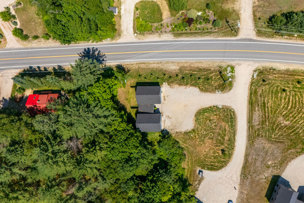 An aerial view highlights the property’s setting, convenient road access, and spacious parking area.
