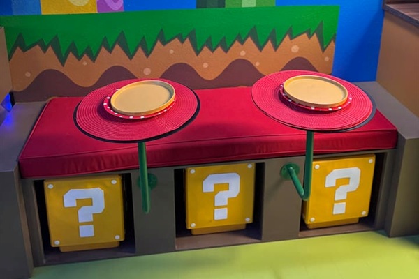 Family-friendly Mario breakfast nook at Mario's Mini Mansion in Clermont, FL! Red cushioned bench, question mark block stools (removable), and giant Piranha Plant mural create a fun spot for pancakes and morning smiles.