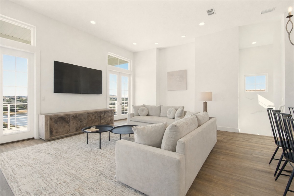 Bright, airy living space with soaring ceilings and balcony access overlooking the water. Sink into plush seating, stream your favorites on the large TV, and gather around for relaxed evenings filled with conversation, laughter, and coastal breezes driftin