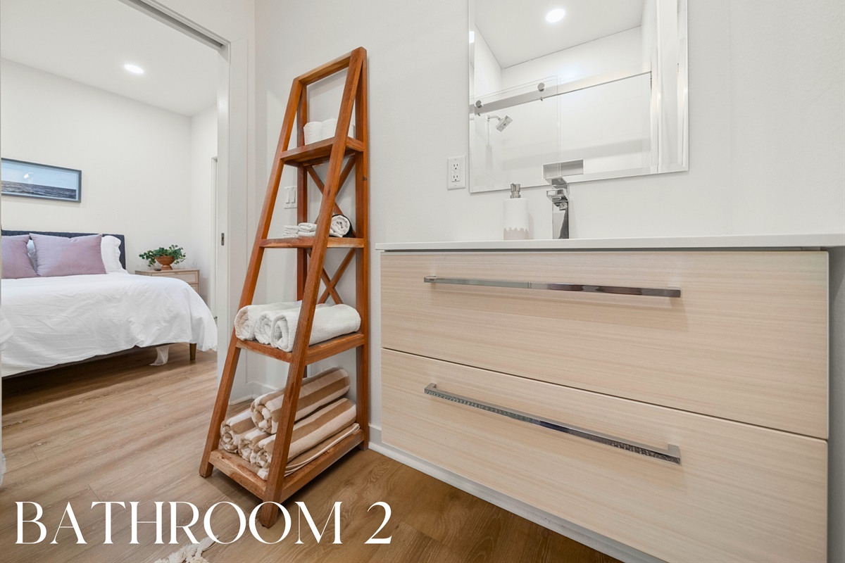 Bathroom 2: Modern vanity and open shelving with fresh linens provided.