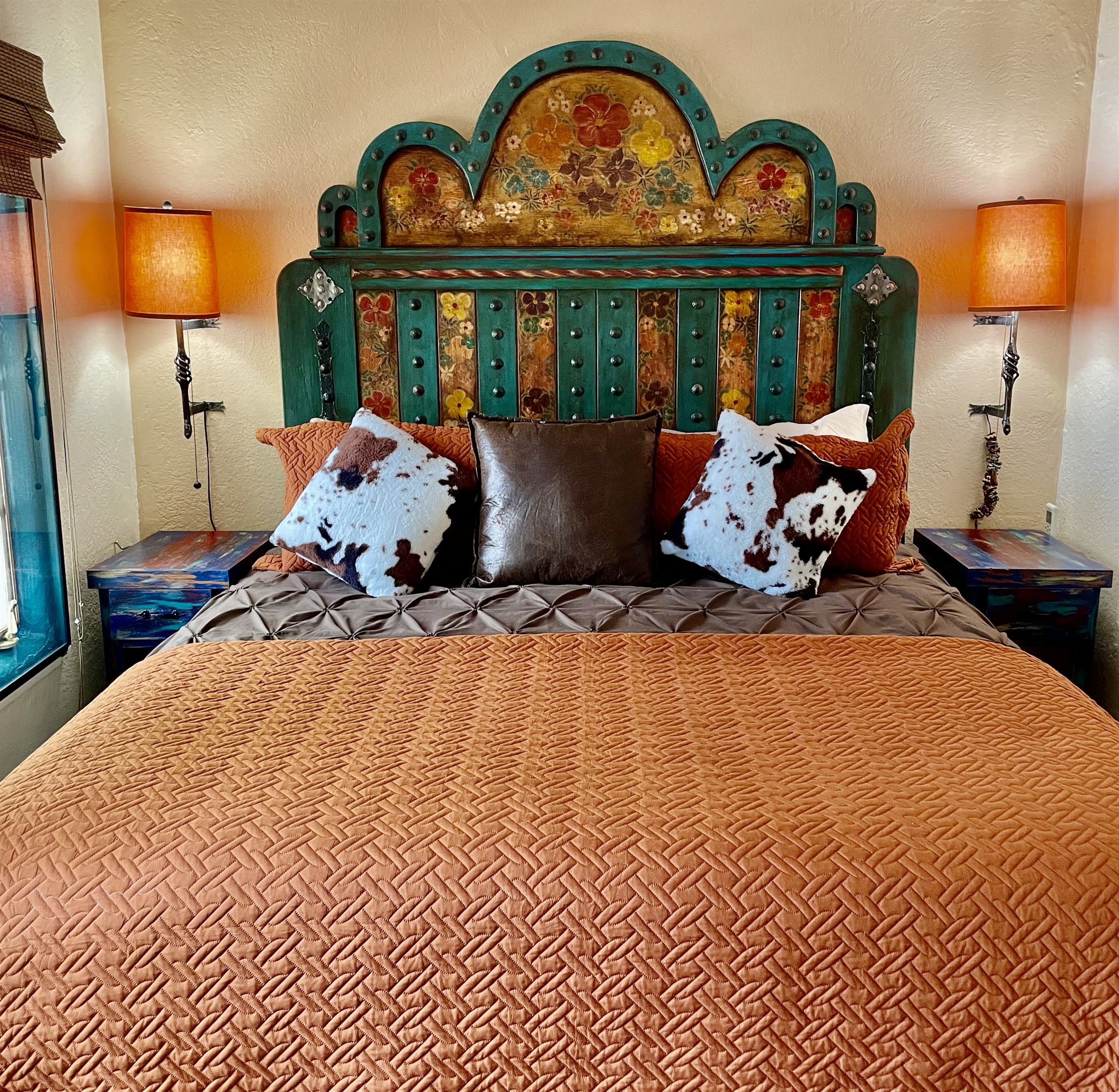 King-size bed with vibrant textiles and artistic accents.