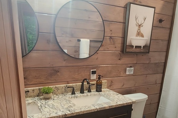 Full bathroom with round mirror, shelf space, and tasteful decor.