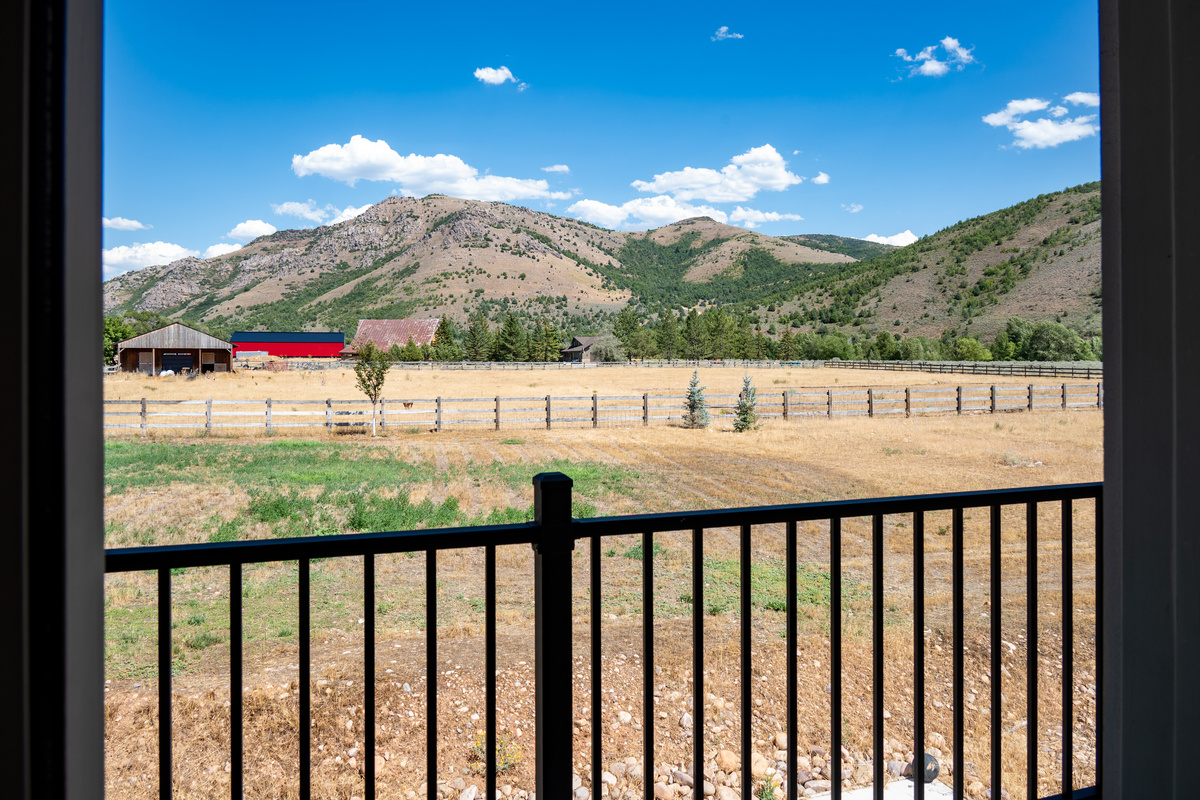 Step onto the private balcony and take in uninterrupted views of open fields, rustic barns, and the surrounding mountain landscape.