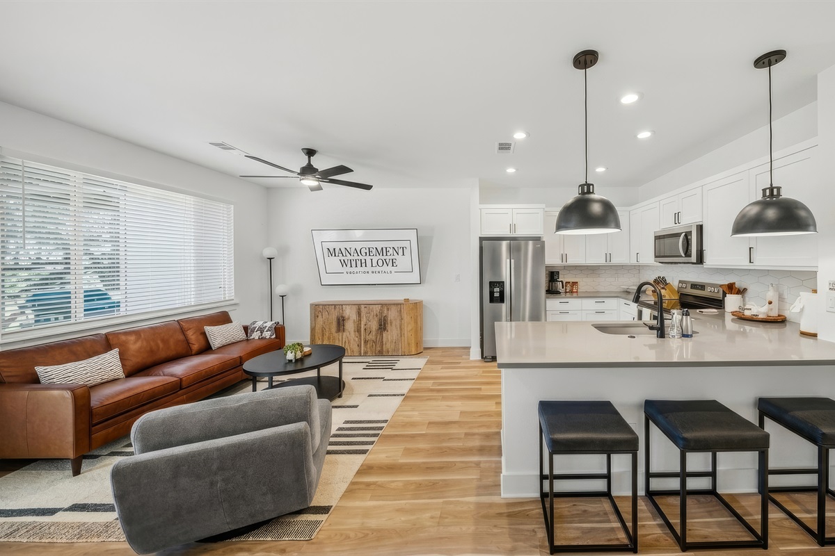 Open concept living room with modern kitchen and island seating.