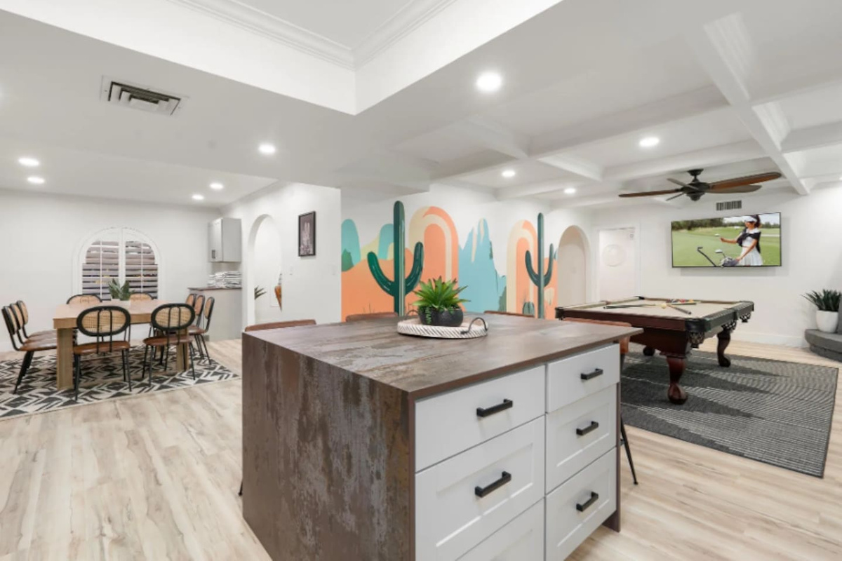 A statement island anchors the kitchen, with a hand-painted cactus mural setting a playful desert tone in the background. Just beyond, the game room invites a little friendly competition after dinner winds down.
