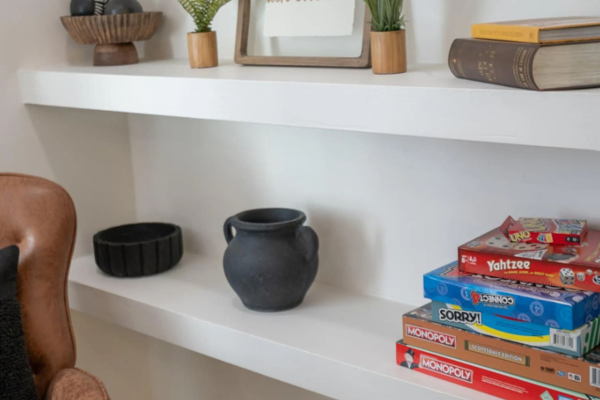 A curated shelf mixes decorative touches with classic board games, a small reminder that there's always something fun within reach.
