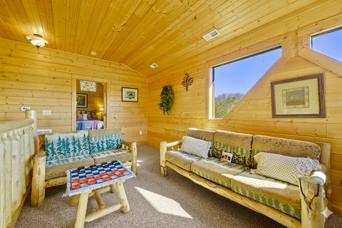 Tucked beneath slanted beams and picture windows, this loft nook invites you to curl up, read a book, or take in the mountain views bathed in golden light featuring a twin sofa bed, perfect for extra sleeping space or a quiet spot to relax.