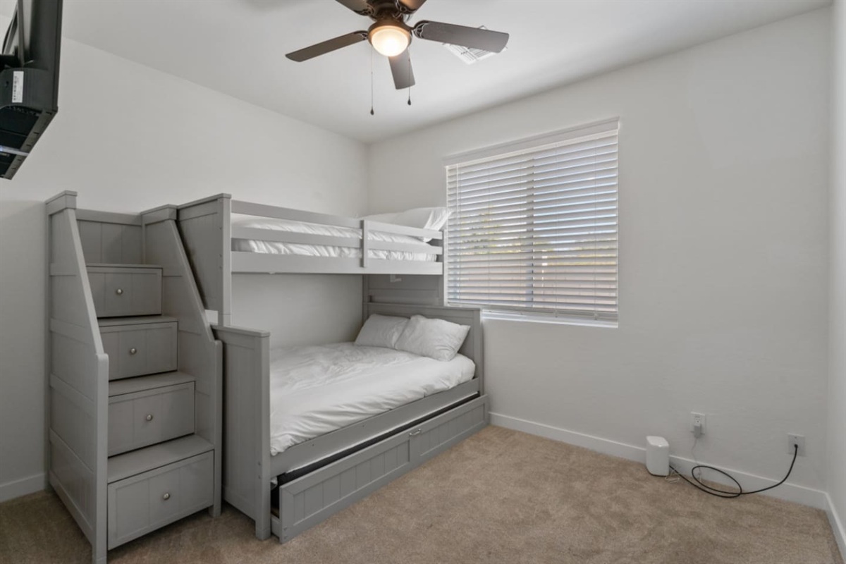 Guest Bedroom 3 with bunk-style sleeping, trundle bed, ceiling fan, and a flexible setup for kids or extra guests.