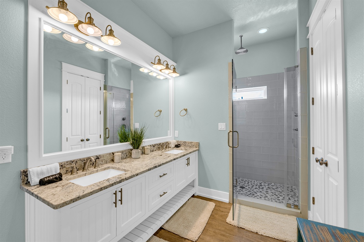 Sea It All: First-floor primary ensuite with walk-in closet, glass rain shower, and dual vanity, your perfect post-beach retreat.
