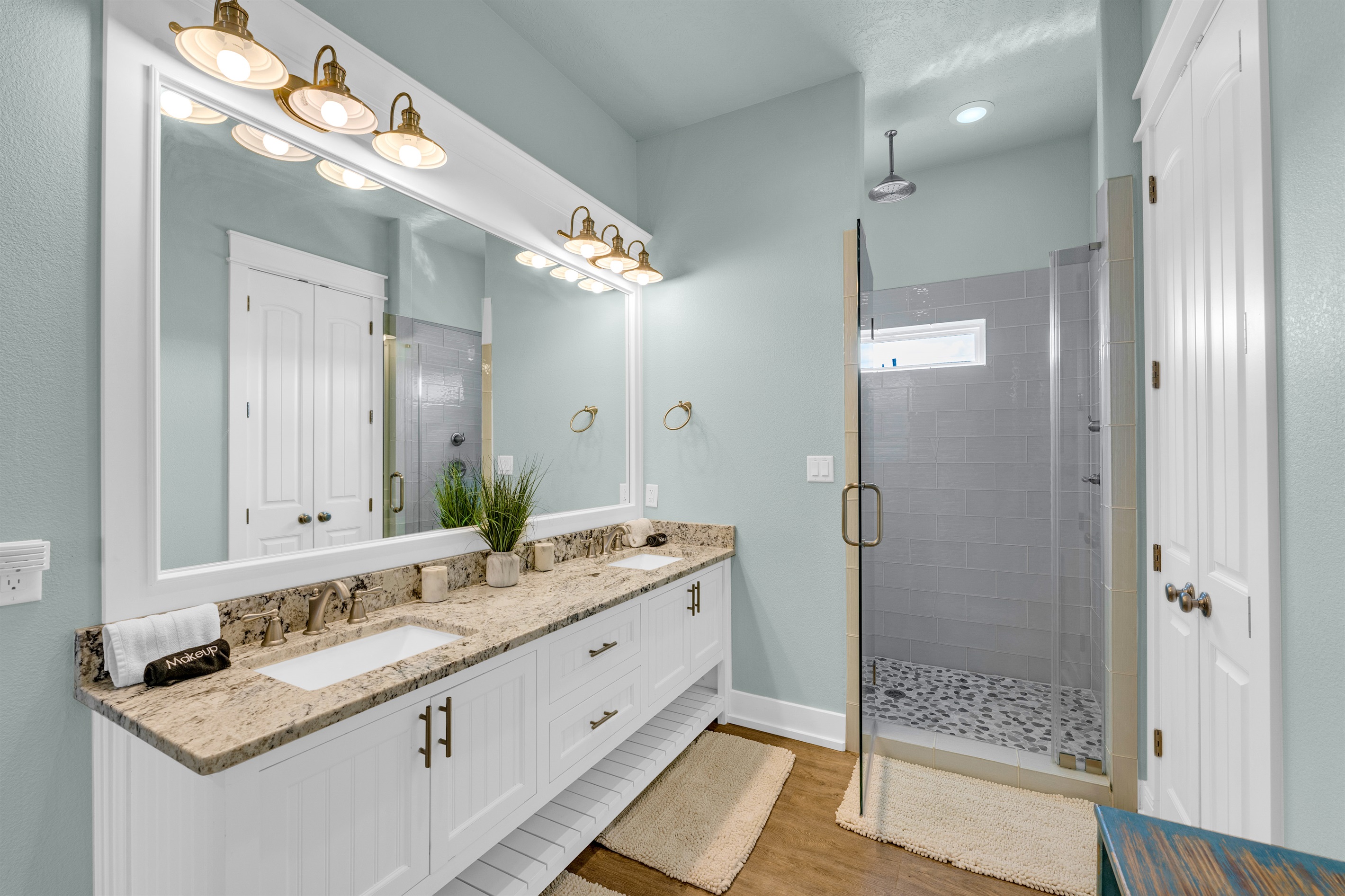 Sea It All: First-floor primary ensuite with walk-in closet, glass rain shower, and dual vanity, your perfect post-beach retreat.