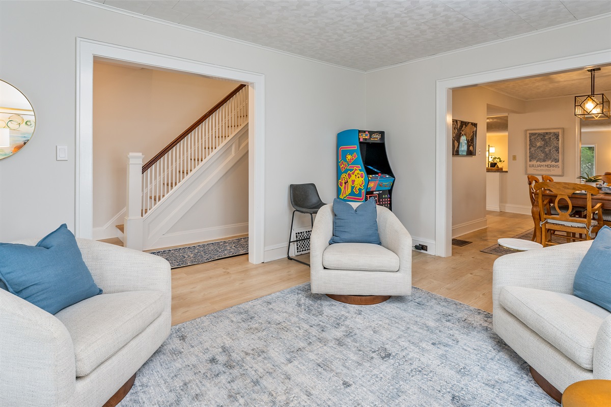Fun meets comfort in this chic living room featuring a retro arcade game, ideal for game nights or casual lounging.