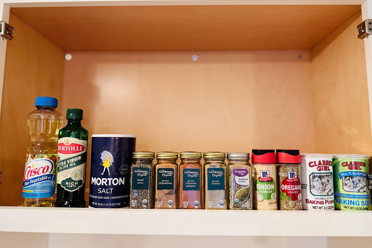 Pantry cabinet includes cooking oils, spices, and basic baking supplies.