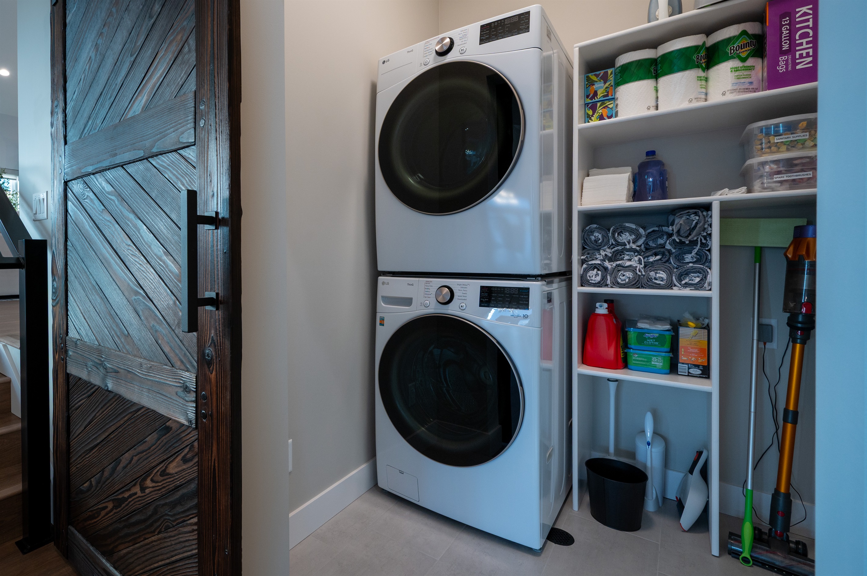 Laundry closet equipped with washer, dryer, fresh towels, and essential supplies for your stay.