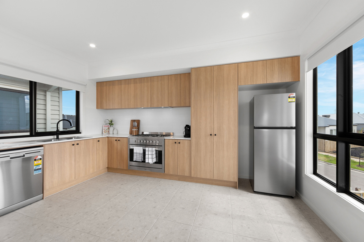 Fully equipped kitchen with a fridge/freezer, dishwasher, oven and plenty of timber cupboard space, with natural light from the window.