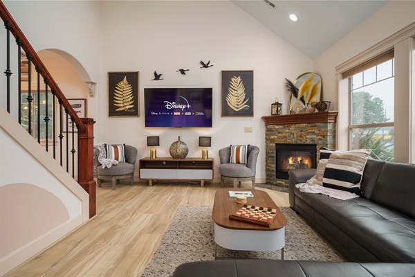 As you enter the living room, the warmth of the fire immediately envelops you, casting a cozy glow over the entire space. The room is elegantly furnished, with plush sofas and armchairs arranged around the fireplace, inviting you to sit and relax.
