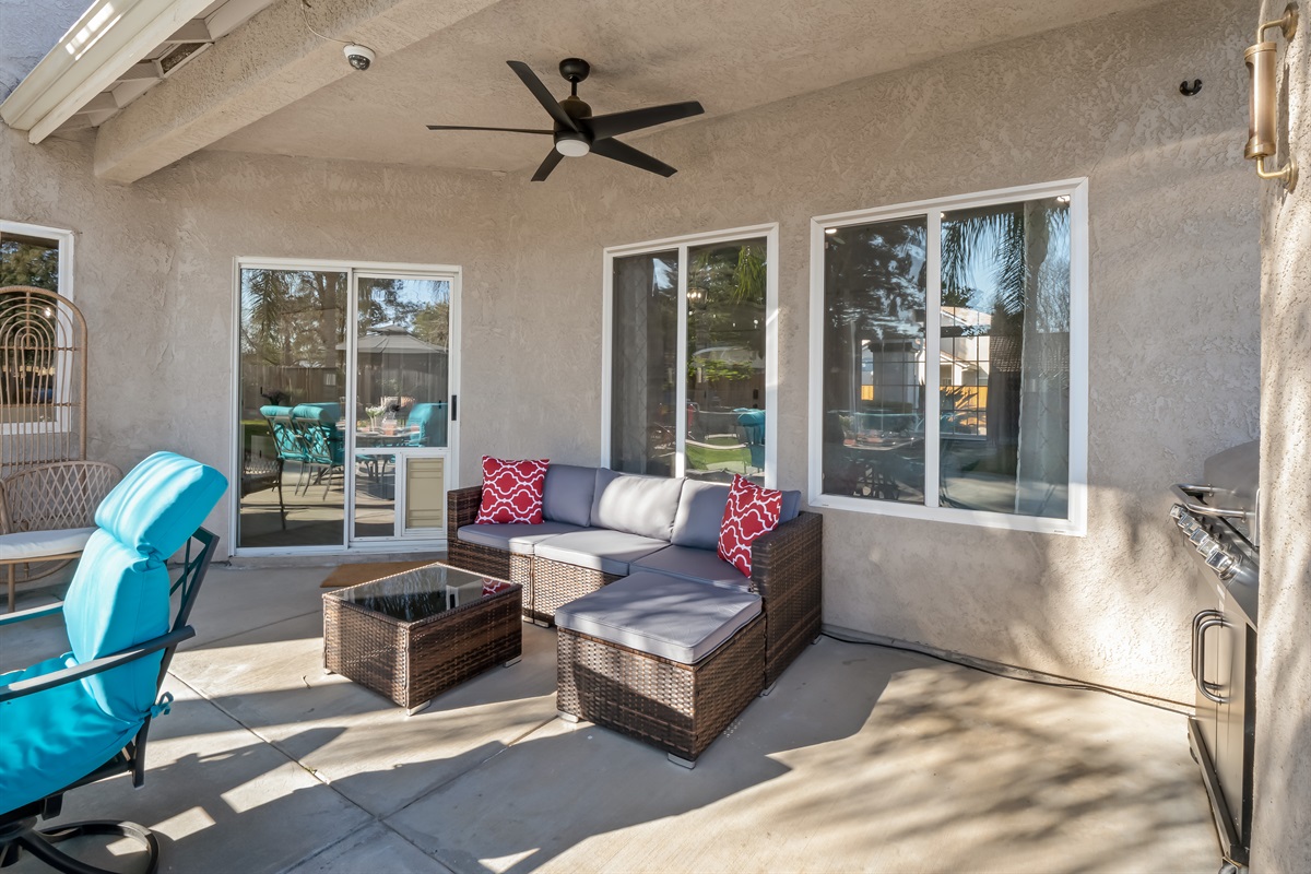Shaded patio with ceiling fan, stylish wicker seating, and outdoor grill offers a true private-resort experience.