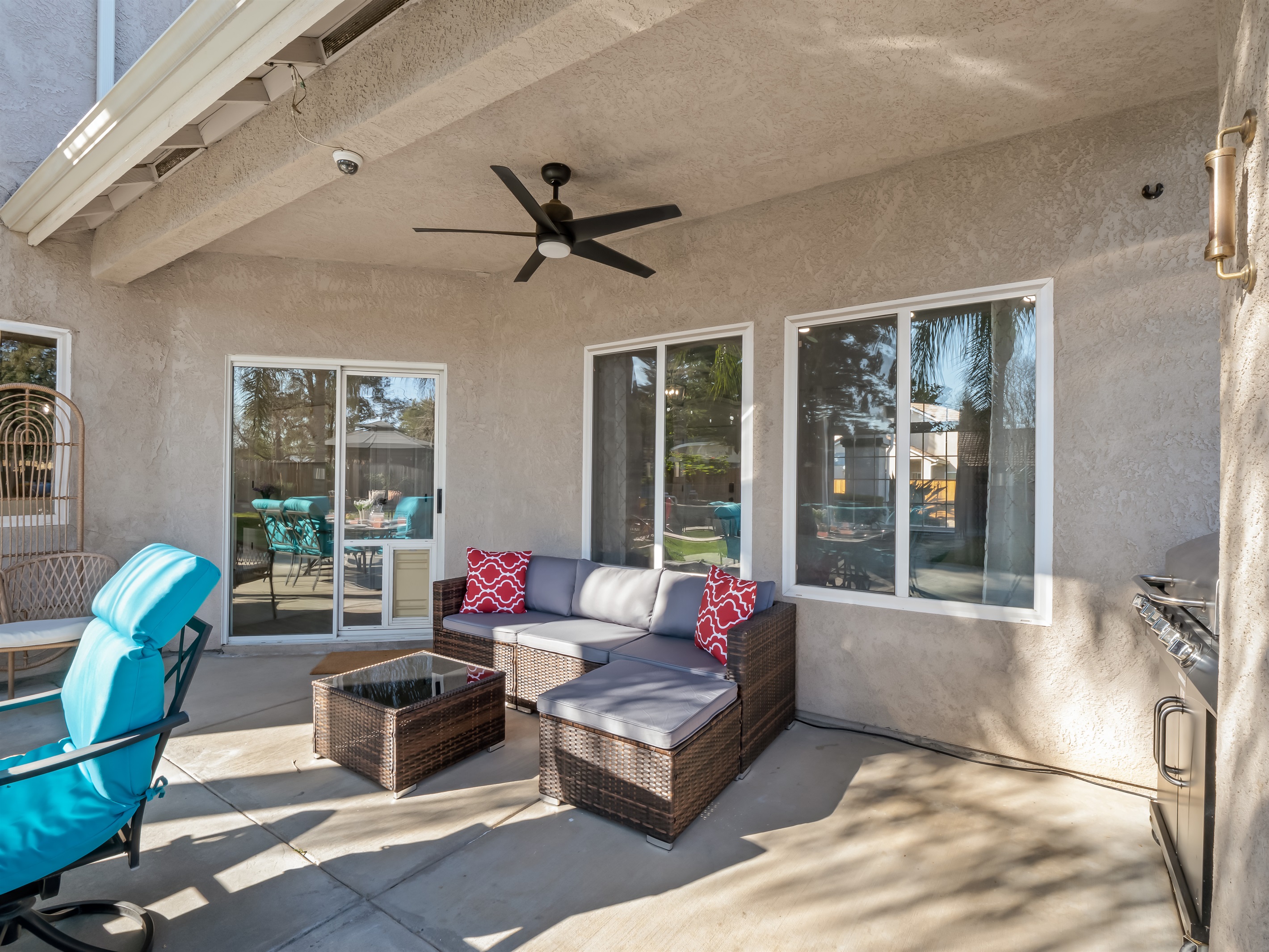 Shaded patio with ceiling fan, stylish wicker seating, and outdoor grill offers a true private-resort experience.