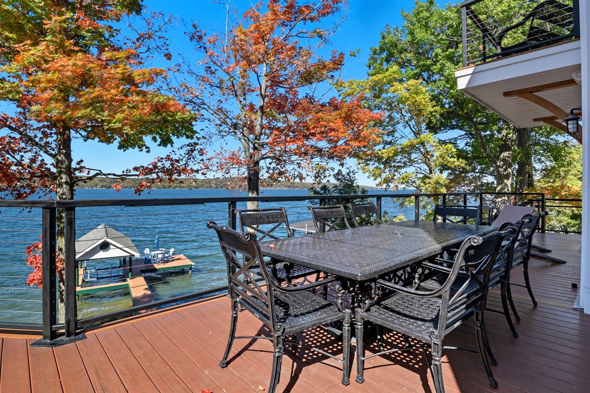 Spacious deck with multiple seating options by the lake.