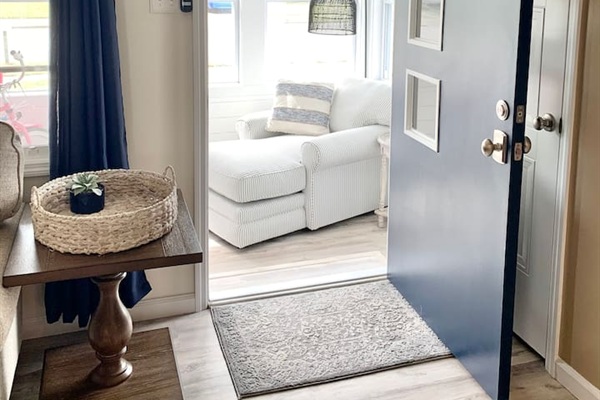 Welcome home! The navy front door opens into a bright, airy entryway that leads directly into a sun-drenched lounge area. With coastal accents and warm wood tones, it’s a beautiful first impression for your seaside getaway.