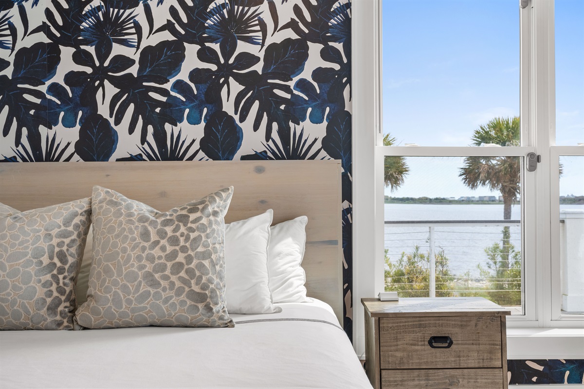 Elegant king retreat with designer accent wall, plush bedding, and plenty of natural light throughout