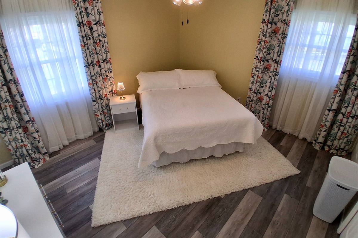 This room has a queen bed with a comfy 12" cooling foam mattress & a dresser. Guests love the peaceful half-acre backyard view. And yes—there’s a sleek black urinal in the private bathroom, a playful nod to comfort and style.