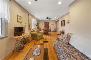 Living room featuring floral couch, tv, armchair and dining room in the background.