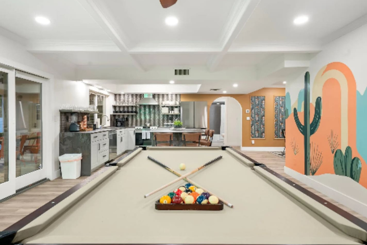 Rack 'em up on the full-size pool table, with the kitchen and a vibrant cactus mural just beyond, keeping everyone connected while the game's on.