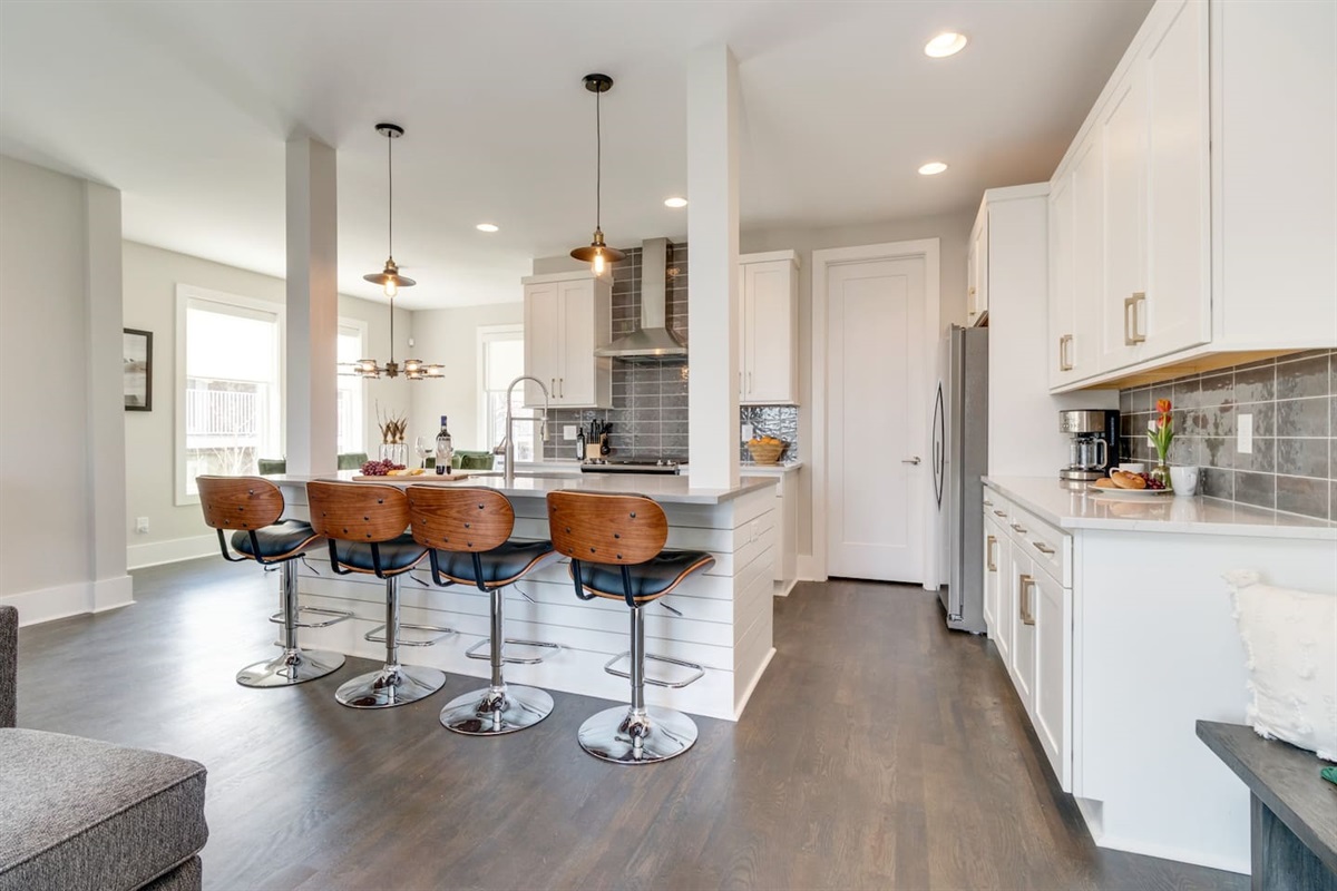 - Kitchen with sleek white cabinetry, quartz counters, & stainless steel appliances - Spacious island with seating for four & pendant lighting ideal for gathering & dining - Subway tile backsplash & open layout create a modern, welcoming culinary space
