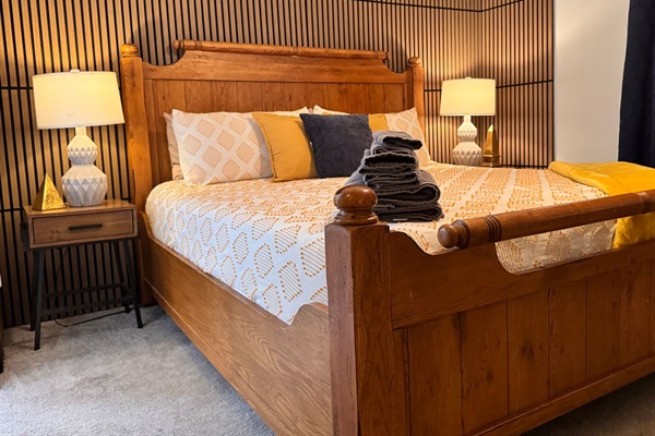 King-sized bed with an en-suite bathroom and walk-in closet. It includes blackout curtains, a full-length mirror, 50” TV, side chair, and table, as well as USB and USB-C charging ports & Pak-N-Play portable crib.