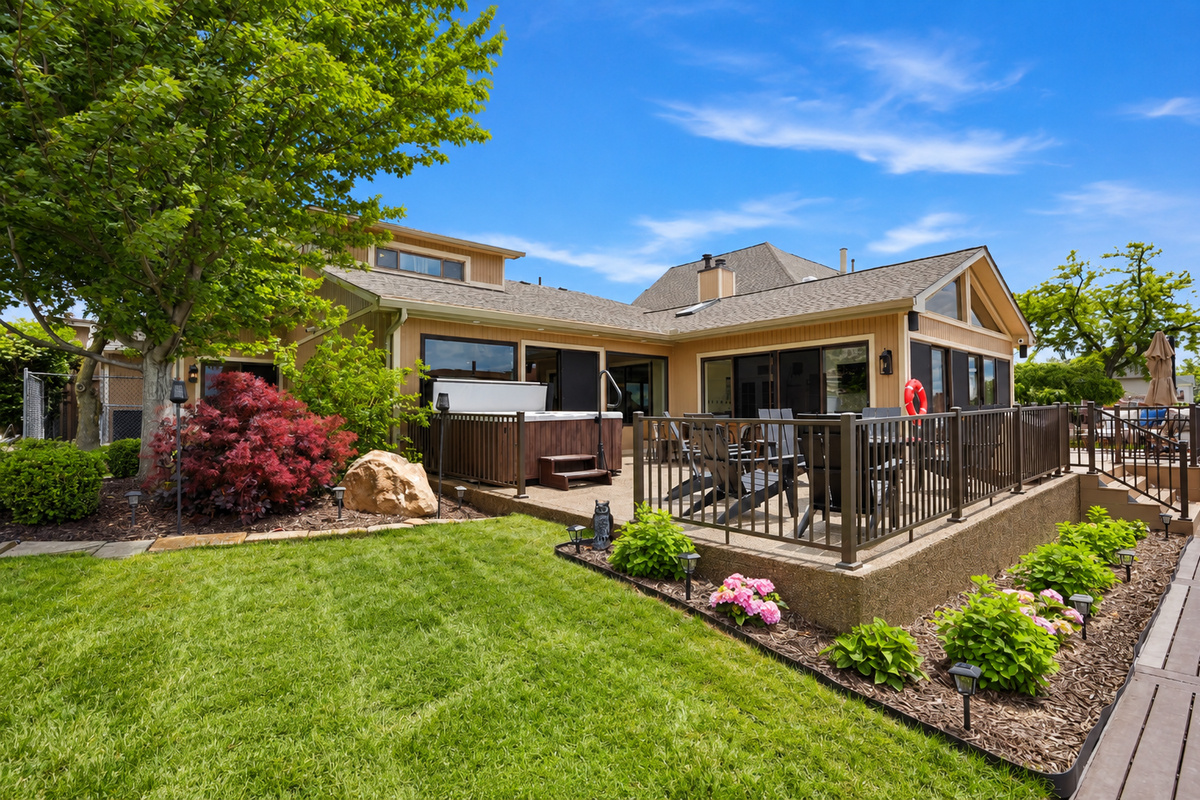 Spacious backyard patio with a hot tub, outdoor seating, and well-maintained landscaping. Private and relaxing outdoor space perfect for entertaining, unwinding, and enjoying warm-weather stays.