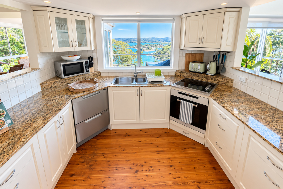 The kitchen at Carinya Coastal Escapes includes granite benchtops, a dishwasher, cooktop, oven and plenty of bench space for easy meals.